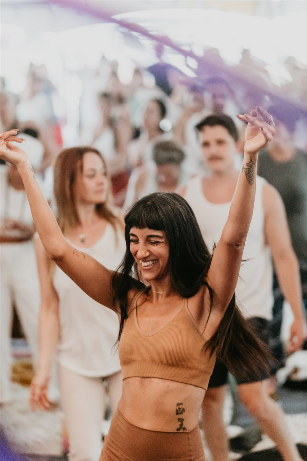 Woman dancing joyfully with arms overhead during practice