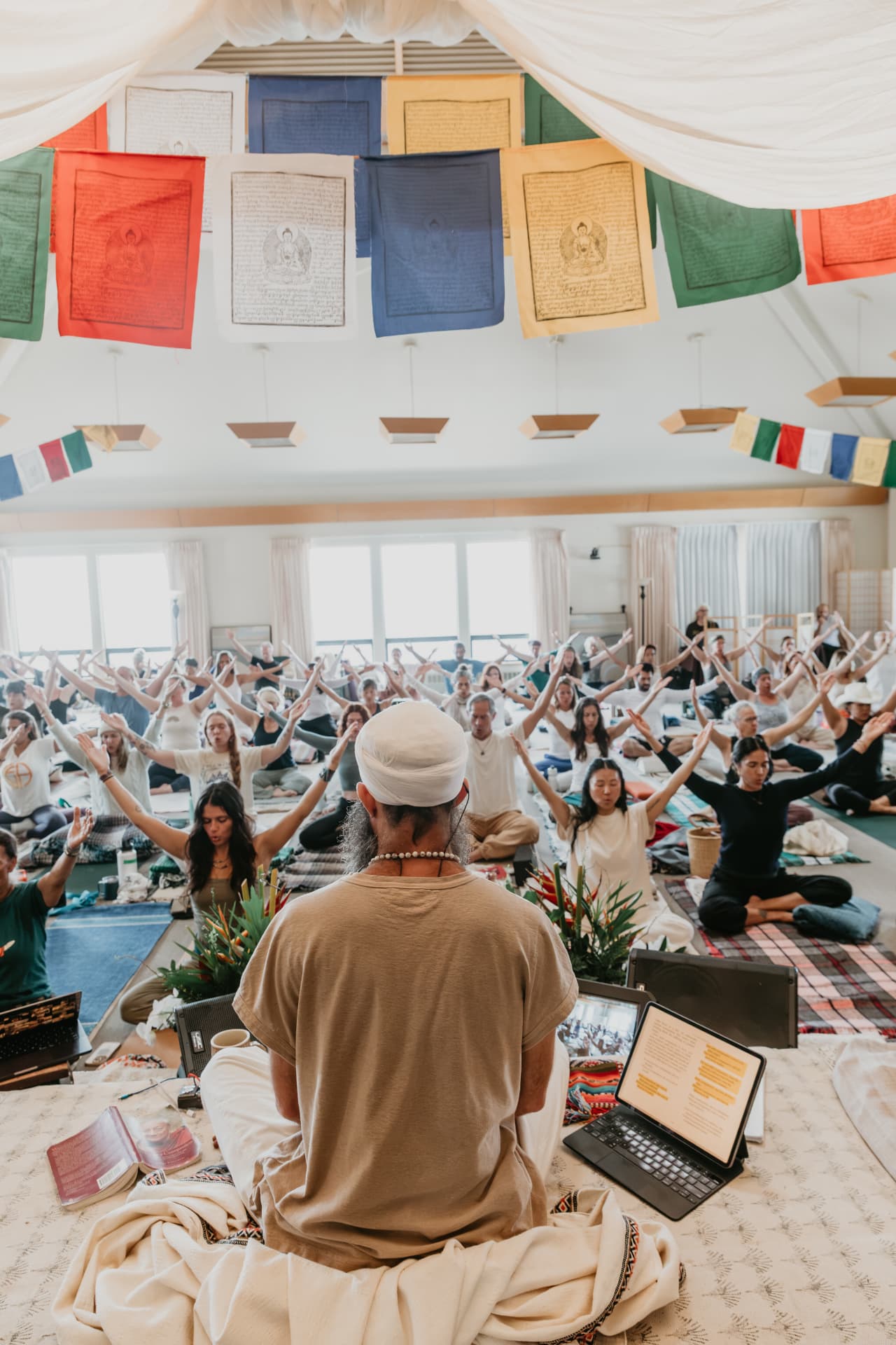 Teacher seated before a full room of students with arms extended