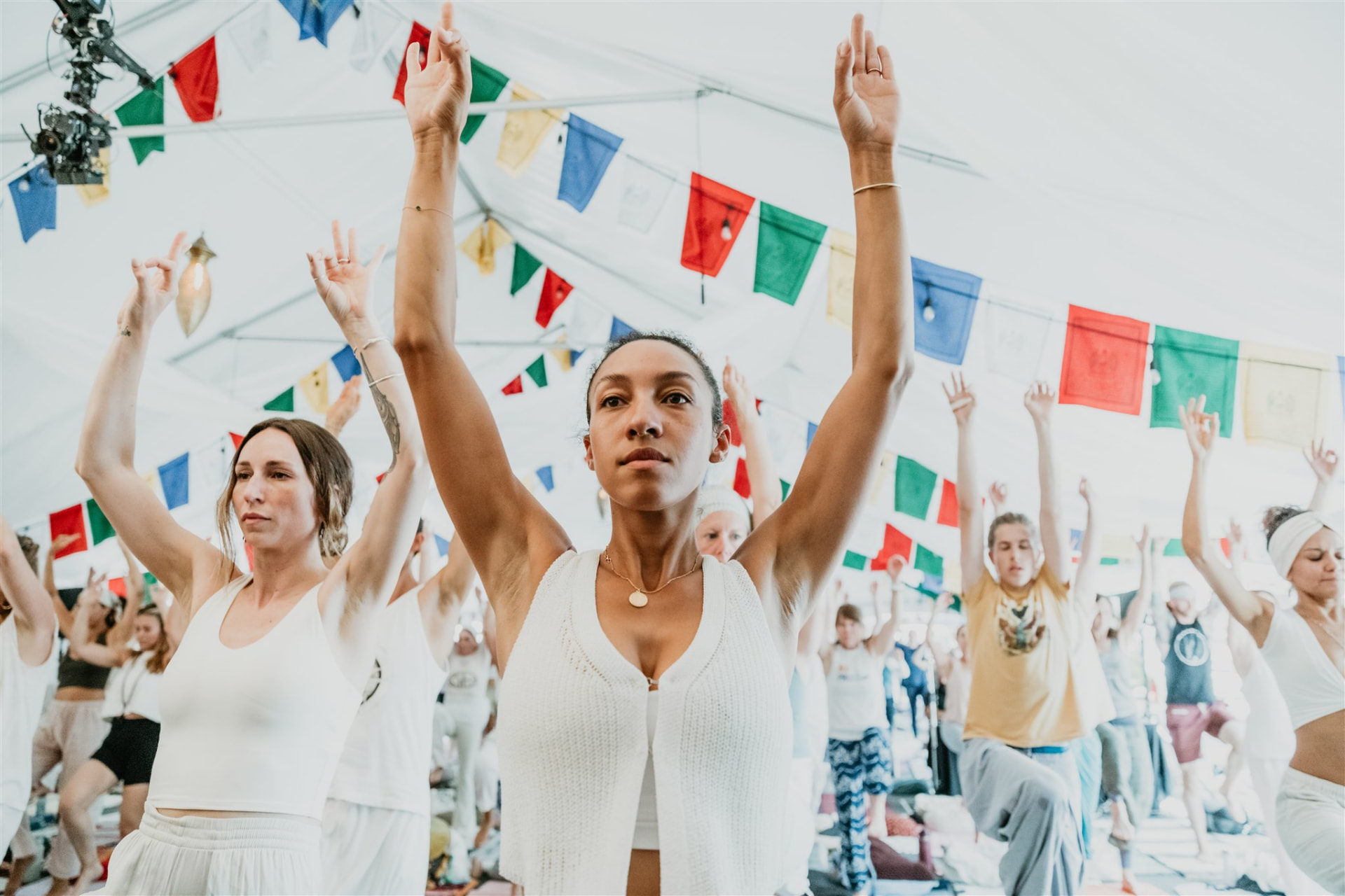Participants with arms raised beneath colorful prayer flags