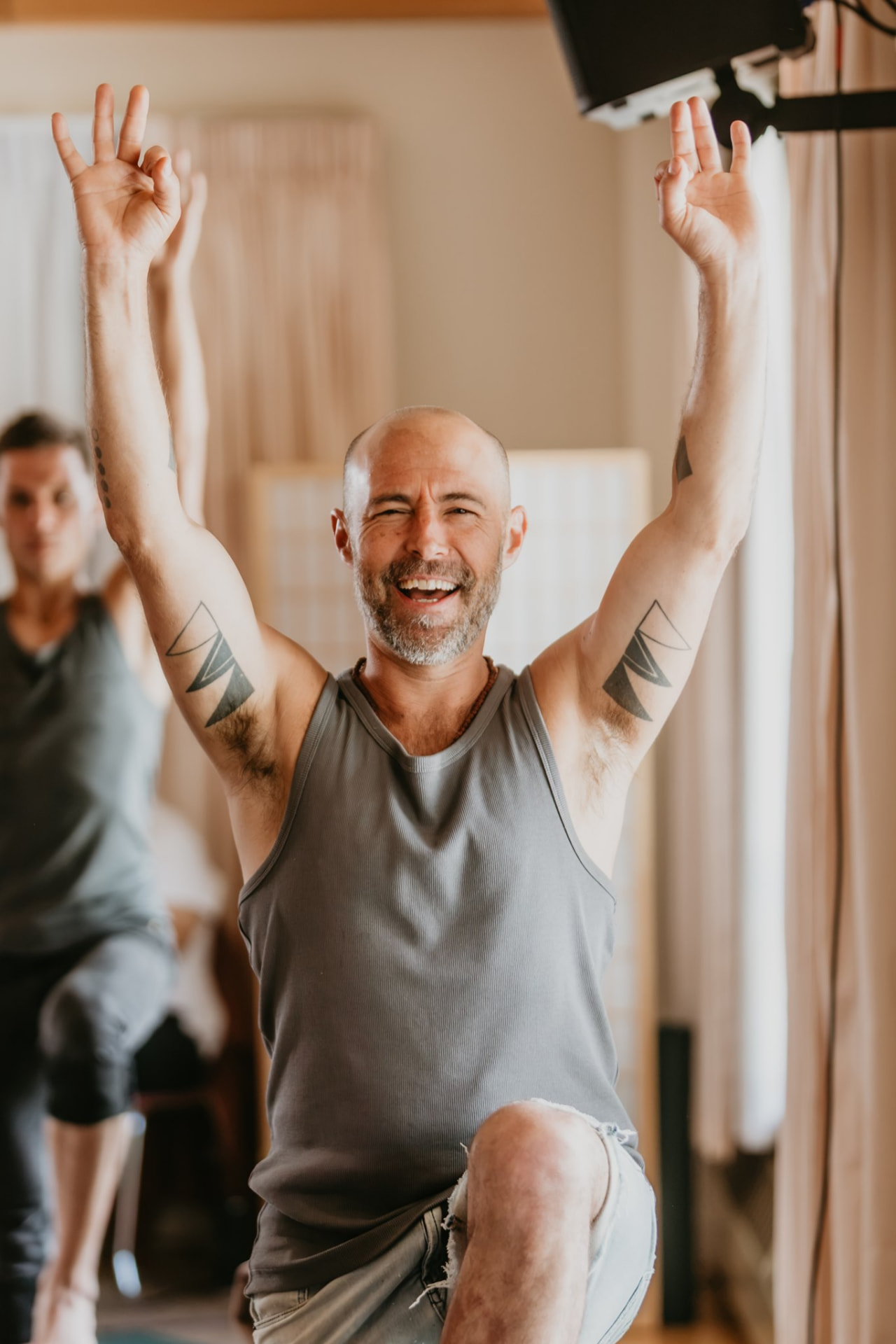 Smiling participant with arms raised in practice
